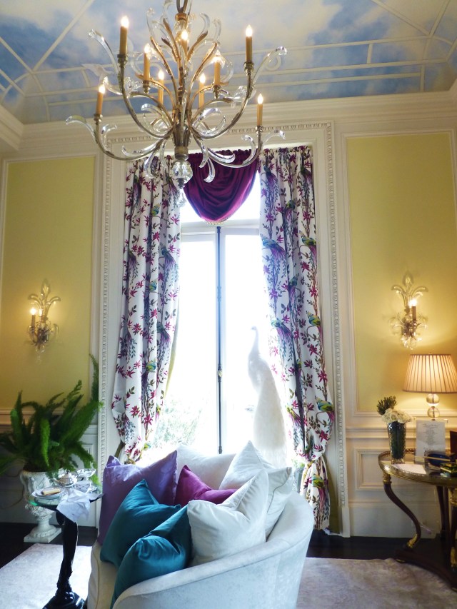Beautiful saturated colors are featured in this stimulating space. Notice the hand-painted ceiling and bold-colored pillows on the sofa. A taxidermy peacock is placed in the window (a popular theme at this year's house).