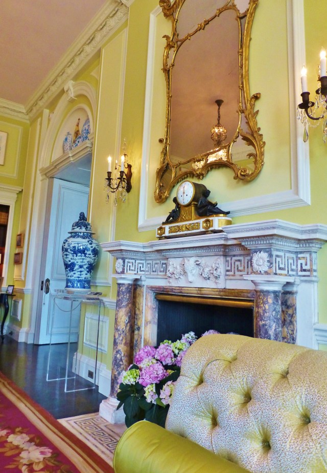 The original fireplace mantel shines when surrounded with this chartreuse green wall color and fabrics.  Blue and white porcelains are also a feature in the space.