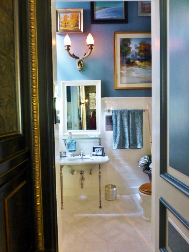 The wall colors and fabrics were chosen to bring the rich feel of the Billiard Room into the Gentlemen's Wash. I love the gallery wall of colorful artwork, which goes all the way to the ceiling in this small space, giving it an expansive feel.