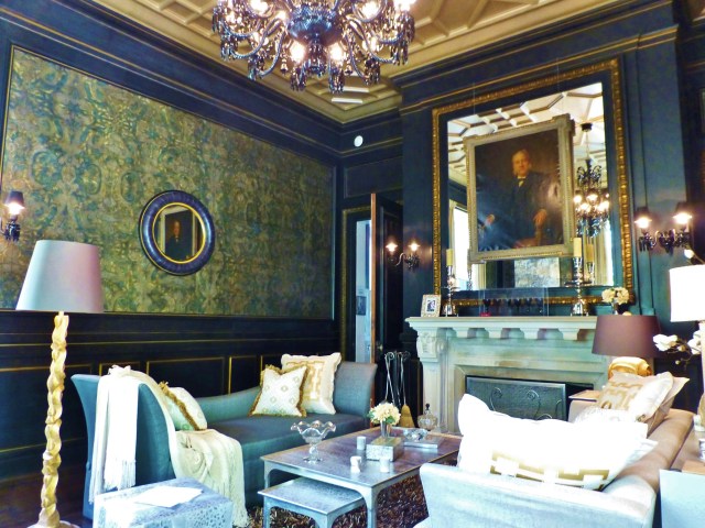 Luxurious finishes are found throughout this room, from the embossed leather wall-coverings, to the black paneling with gold-leafed details. I love the mirrored over-mantel with a majestic portrait mounted on top!