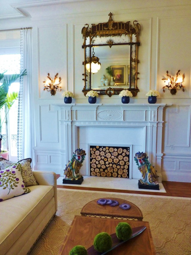 The beautiful original fireplace is topped by a stunning Chippendale mirror and the hearth is flanked by colorful Foo Dogs.  I love how the designer filled the opening with stacked logs (so textural)!