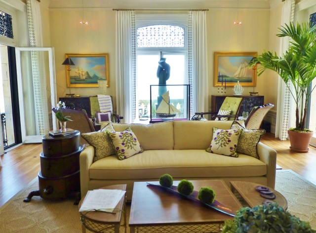 Upon entering the large living room, you are welcomed by a neutral transitional sofa with colorful embroidered pillows.  Notice the purple and green accents found throughout the room!  The extra tall windows are treated to simple white drapery panels with an embellished leading edge.