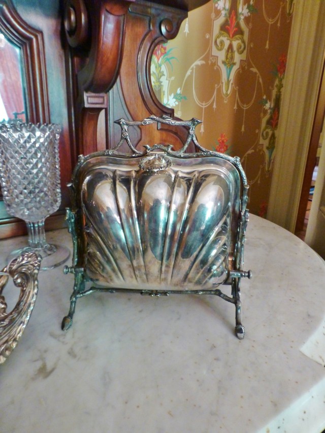 Another fascinating serving piece is this bun warmer, which kept bread and rolls warm during meals. Behind the bun warmer is a handsome Celery Vase, used to keep celery fresh (celery was highly prized and it was believed that celery aided in rheumatism). Many people have these and don't know how they were used. They were very popular Victorian dining room accessories.[/