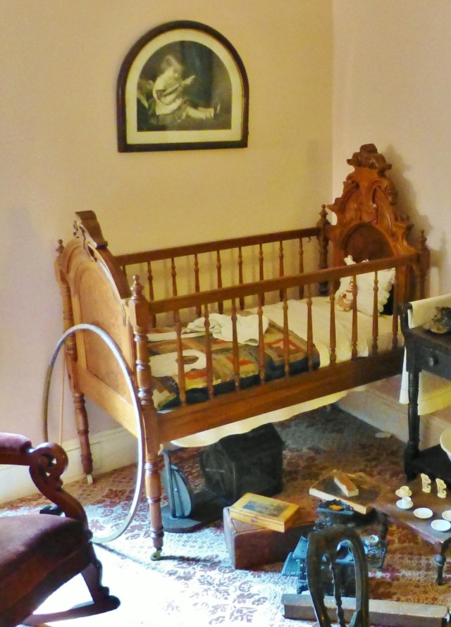 Notice the stick and hoop at the foot of the crib...this was a popular Victorian child's diversion as were the other toys scattered across the floor.  Beneath the crib is an antique squirrel cage--children would often keep squirrels as pets and enjoyed observing them running on the wheel, like hamsters.
