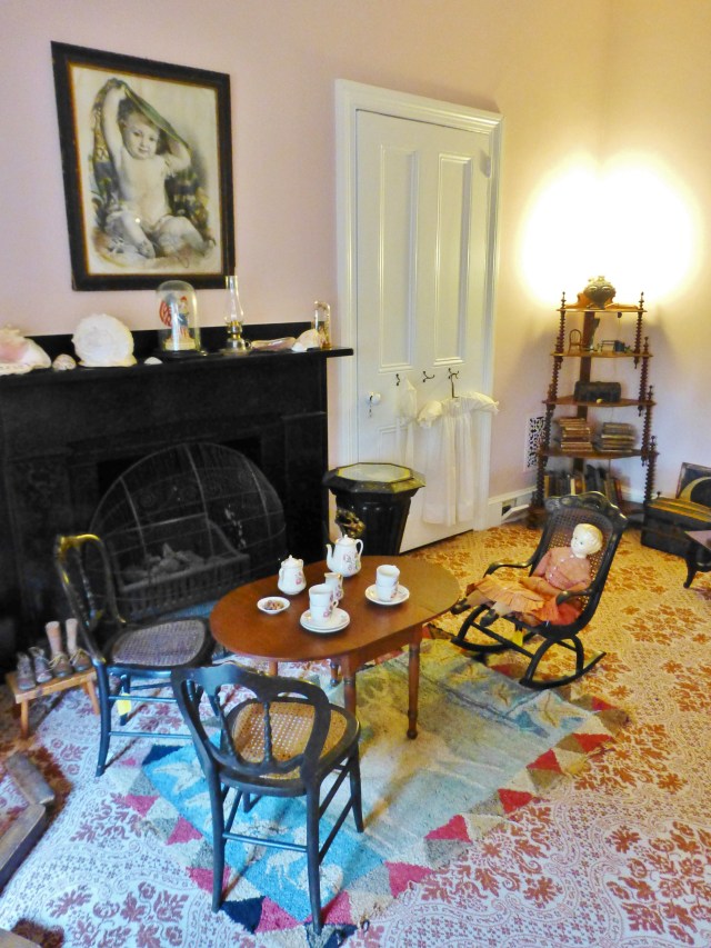 Assembled around the slate fireplace mantel is a child sized table, complete with it's own little hooked area rug and miniature tea set.  Children's tea sets, toys, and furniture in good condition, like these, are relatively rare, since they were often damaged during playtime.  There's even a rocking chair for the antique doll.