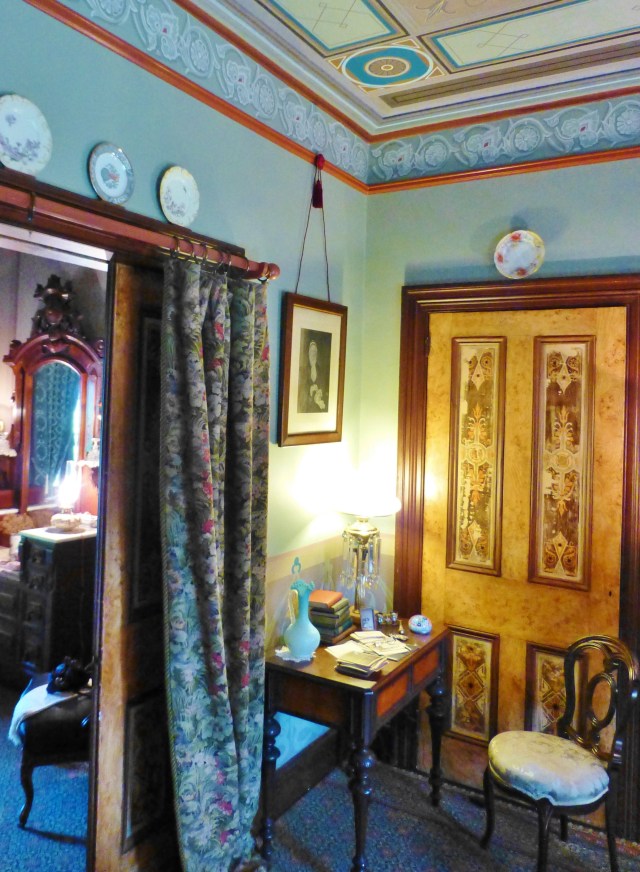 In a corner near the entry to the bedroom, sits a small desk and chair.  This photo shows a door with handpainted woodwork featured in the lounge.  You'll also notice the draperies on the pocket door.  These are called Portieres and, in addition to being decorative, helped to further divide and provide insulation between the spaces.
