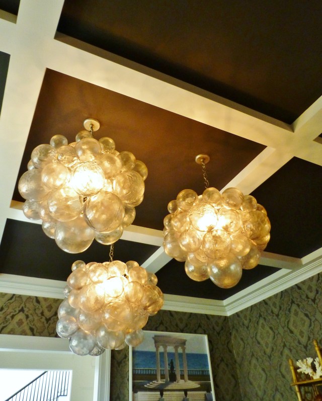 The cluster of three large bubble-like chandeliers draws you eye to the dramatically dark-painted coffered ceiling.