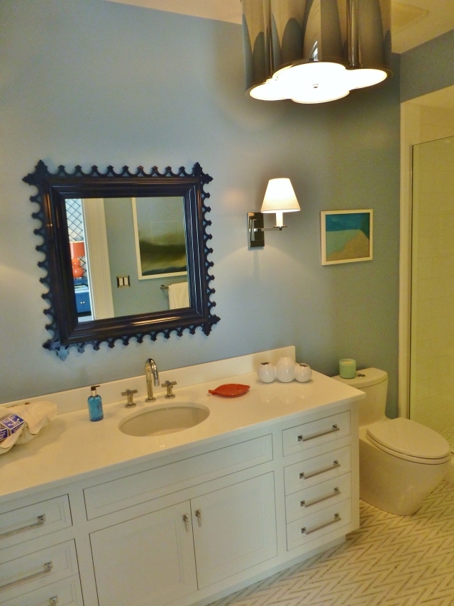 This bedroom has its own private bath, painted in a soft blue.  The designers chose a cute navy blue lacquered mirror and a terrific shiny nickel quatrefoil light fixture.