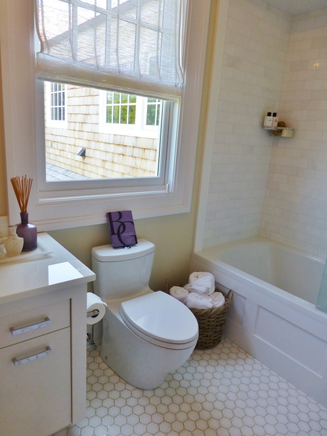 Here's just a quick peek into the en-suite bathroom.  Notice the honeycomb tile on the floor, which is especially nice.  The sheer roman shade is also pretty, but doesn't seem like it would provide much privacy.  Purple accessories are used sparingly to continue the bedroom's color scheme.