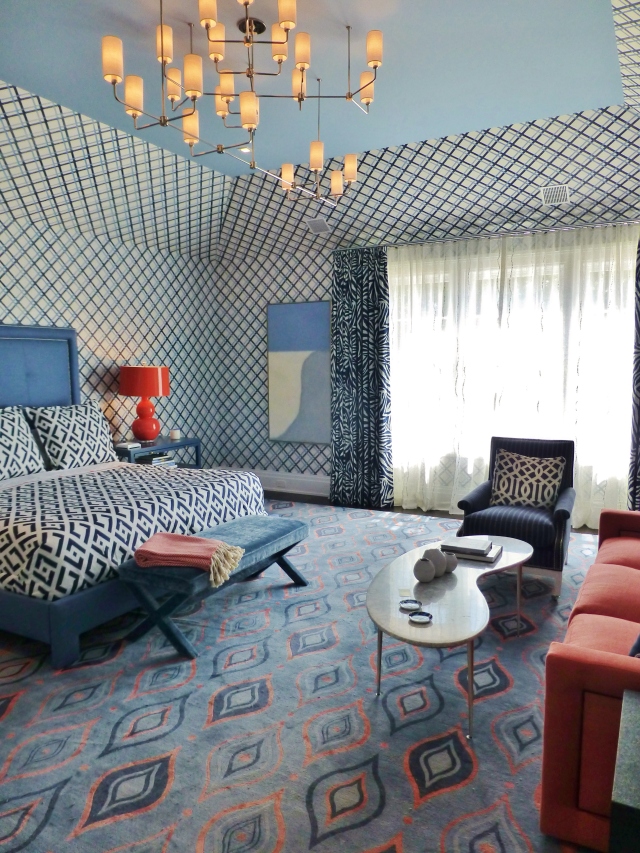 The blue and orange guest bedroom designed by Mabley  Handler Interior Design.  Notice the bold trellis pattern wallpaper wraps up and onto the side of the tray ceiling.  There is a lot of pattern here, but the scale and intensity of each pattern holds its own.
