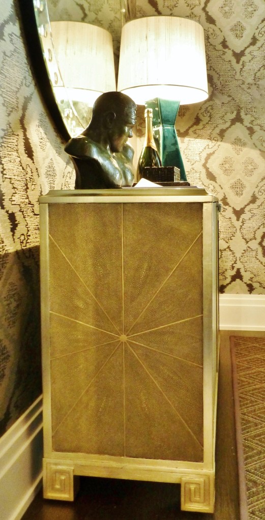 This shagreen cabinet is one of a pair that flanks the glassed in wine enclosure.  Shagreen is a luxurious material commonly made from the skins of sharks and rays.  It's often used to cover books and boxes...even the hilts of swords.  Shagreen is not often used to cover an entire piece of furniture because it is a very expensive substance.  The design of these chests is especially pretty, with the starburst pattern on the side and the silver-leafed details, including the Greek Key feet.