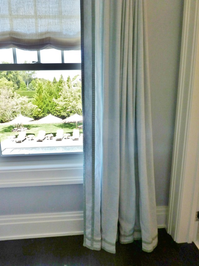 On the windows we find a sheer open weave fabric used for scalloped roman shades.   The drapery panels at the sides are made of a soft blue linen.  A lovely double row of contrasting  gimp was applied at the leading edge and along the bottom for texture and visual detail.  The gimp has a bit of green in it, which is the perfect subtle shift from the palest of blues in the fabric.  
