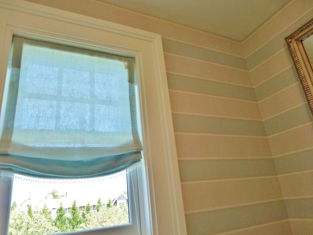 Here's a quick peek inside the en-suite bathroom.  Here a relaxed roman shade was used with a little glass bead trim.  This looks very feminine and pretty with the soft tan and blue horizontal-striped wallpaper.