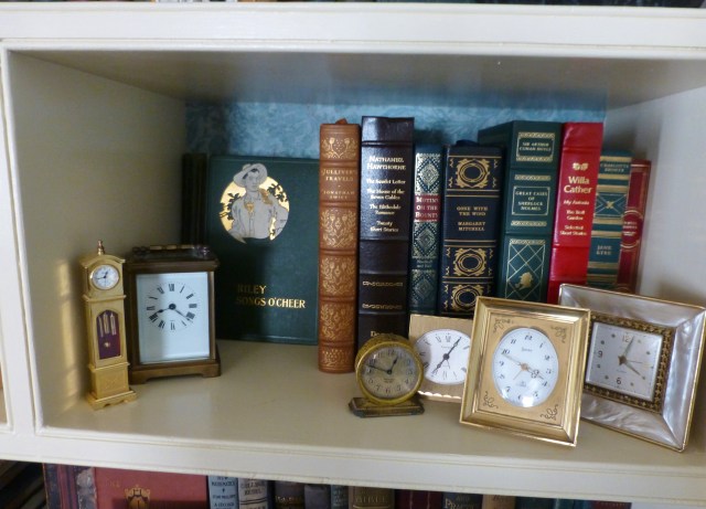 Many of our clocks are displayed in our living room bookshelves, alongside antique and vintage books I've been collecting since High School.  Here you see a grouping of small tabletop clocks, amongst some leather bound books.