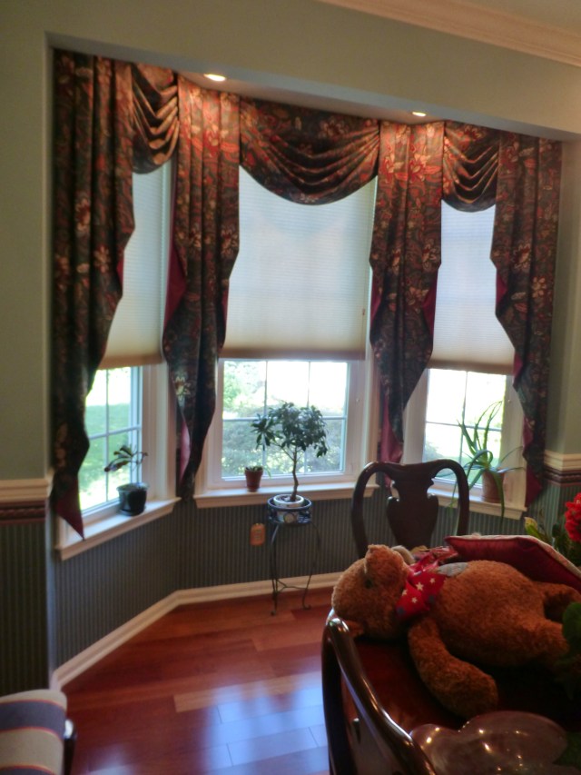 As you can see the dining room is very traditional, with a lovely turquoise paint above the chair-rail and simple darker teal wallpaper beneath. Dark burgundy paisley swags and long cascades feel heavy on this pretty bay window.