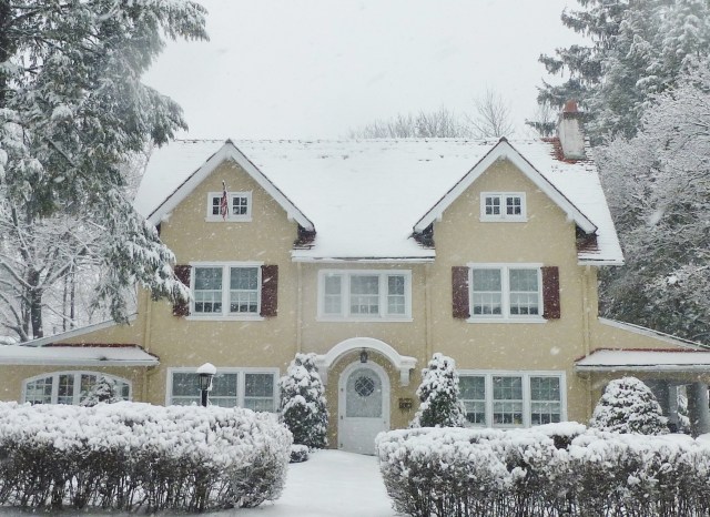 I admire the symmetrical qualities of this pretty tan stucco home.  The two large eaves really draw your eye right down to the charming arched front door.