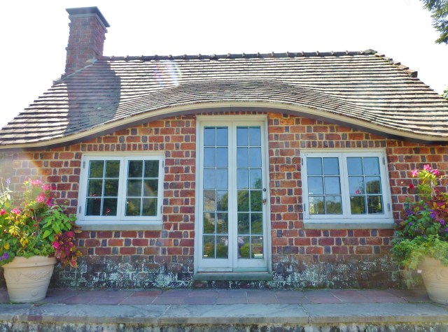 A closeup of the charming English cottage with it's eyebrow roofline.  Notice the detail of the brickwork patterns...who wouldn't love to have such a charming poolhouse?