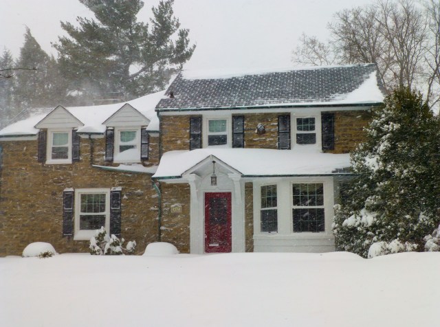 A stone Colonial Style home with its quintessential red door.